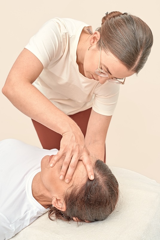 Alina Serafin unterstützt eine Patientin bei einer Pilates-Übung auf einem speziellen Pilates-Chair.